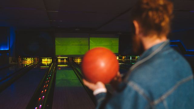 Pistes de bowling éclairées en soirée, joueurs en arrière-plan