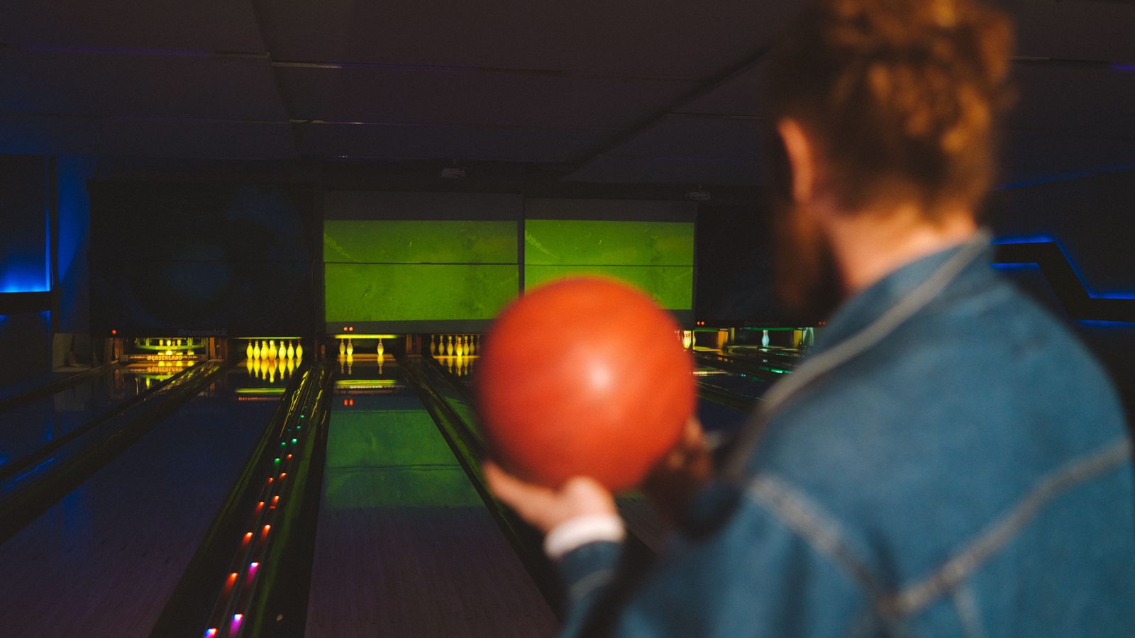 Pistes de bowling éclairées en soirée, joueurs en arrière-plan